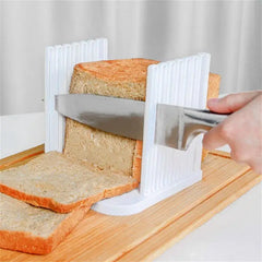 Plastic bread slicer guide with knife cutting even slices on wooden board.