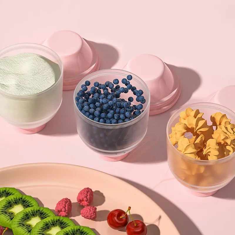 Containers with powder, blueberries, and yellow snacks next to a plate of fruit.